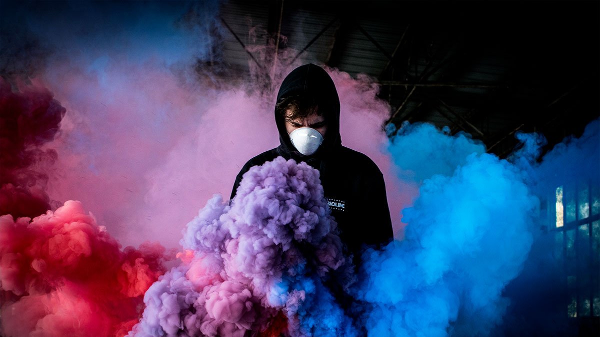 Man wearing black pullover hoodie to smoke light in mask his own